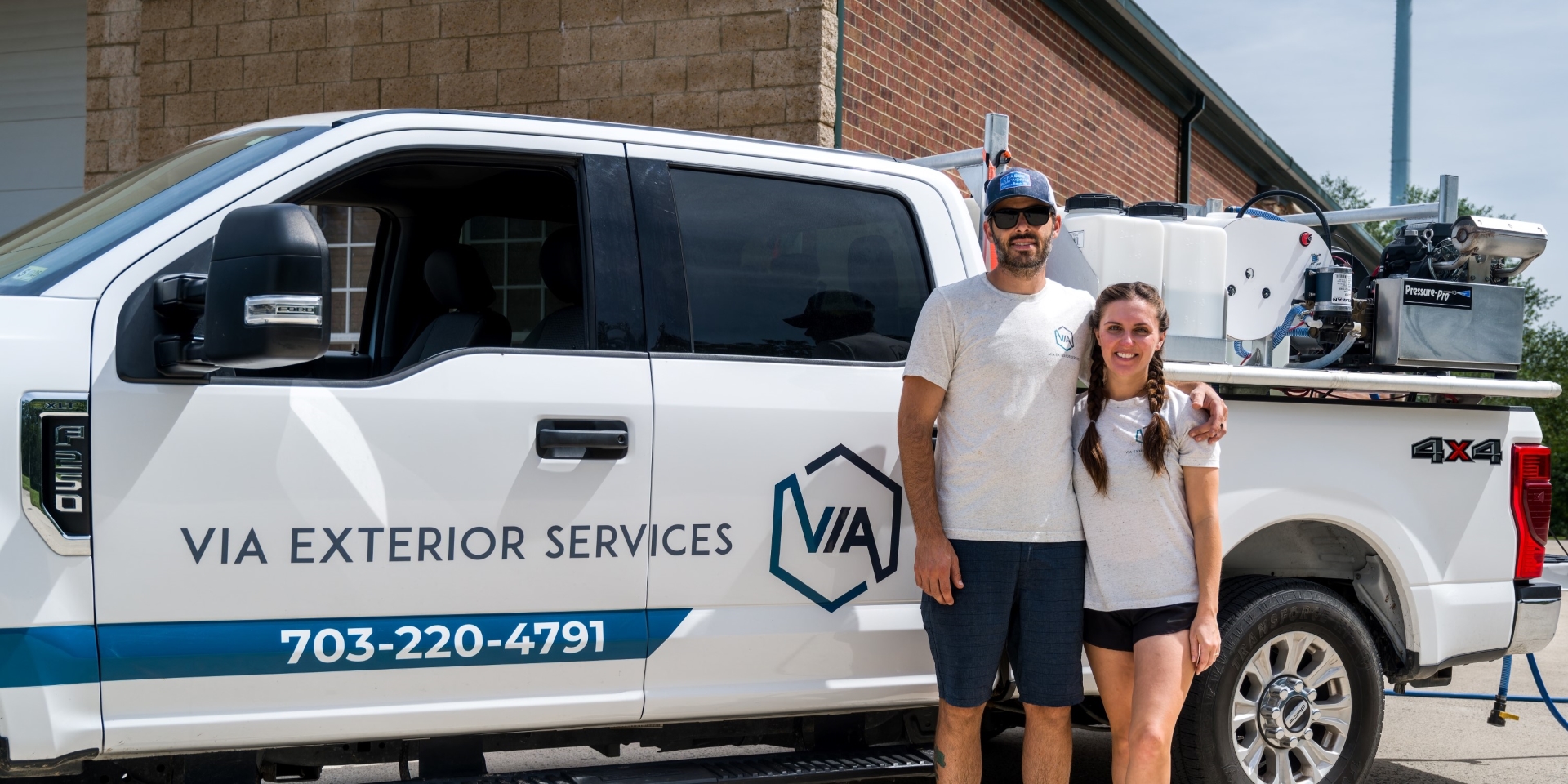 Owners of Via Exterior Services standing in front of pressure washing company's truck.